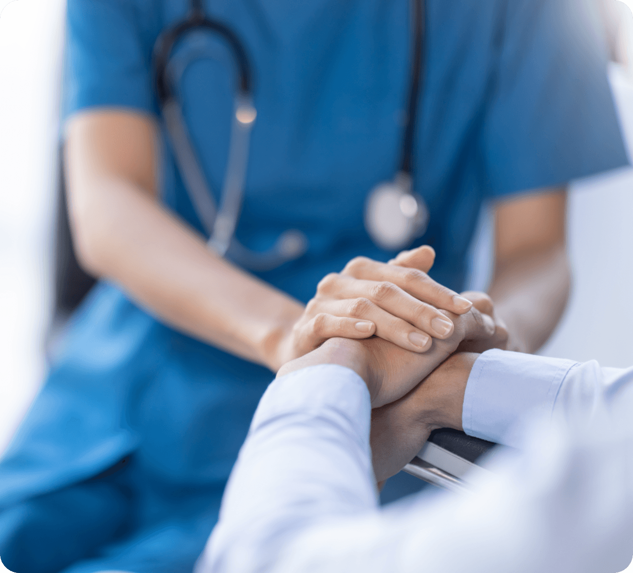 Healthcare professional in scrubs comforting patient by holding hands